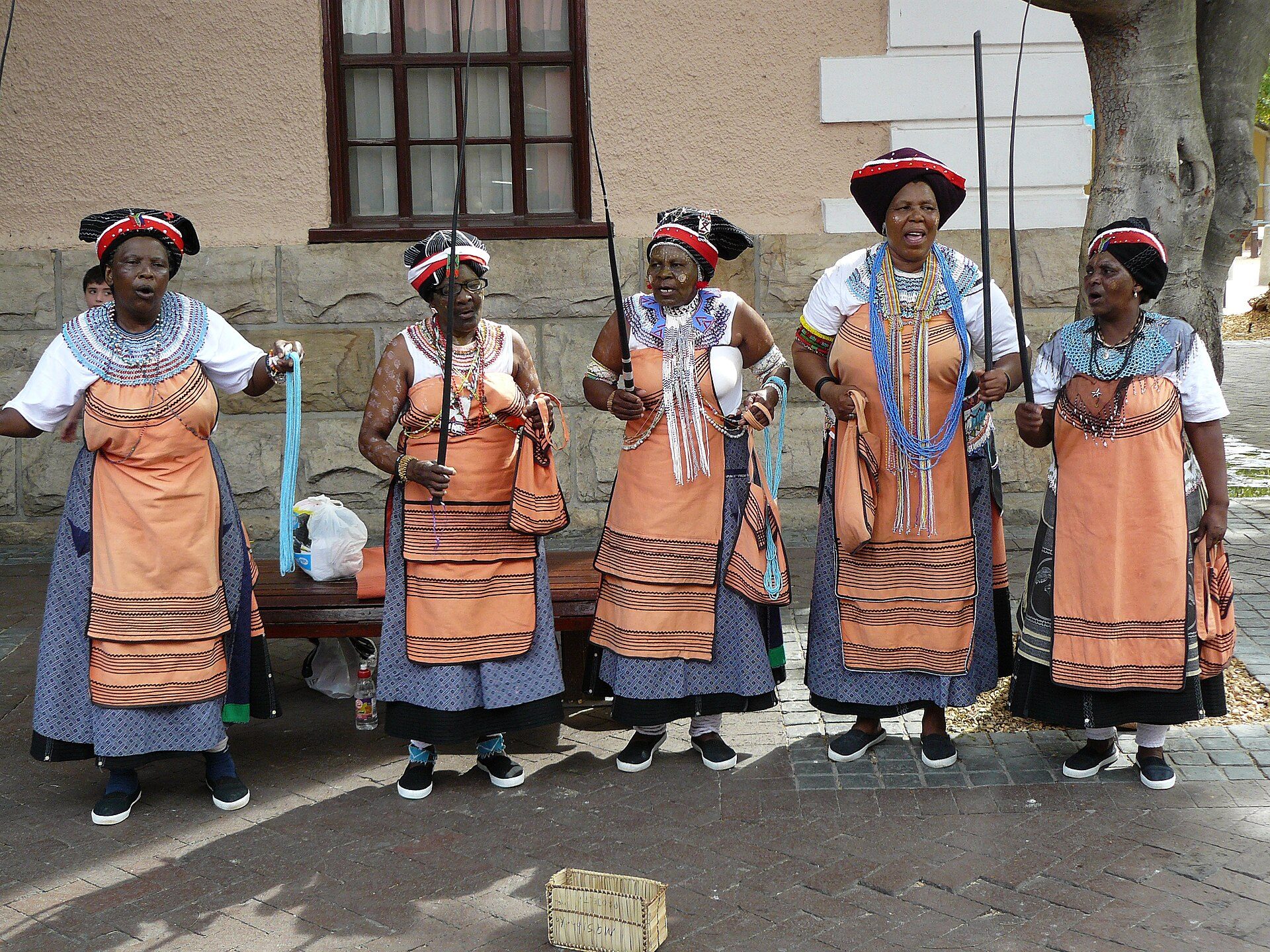 A row of amaXhosa women elders in orange traditional dress and headwraps