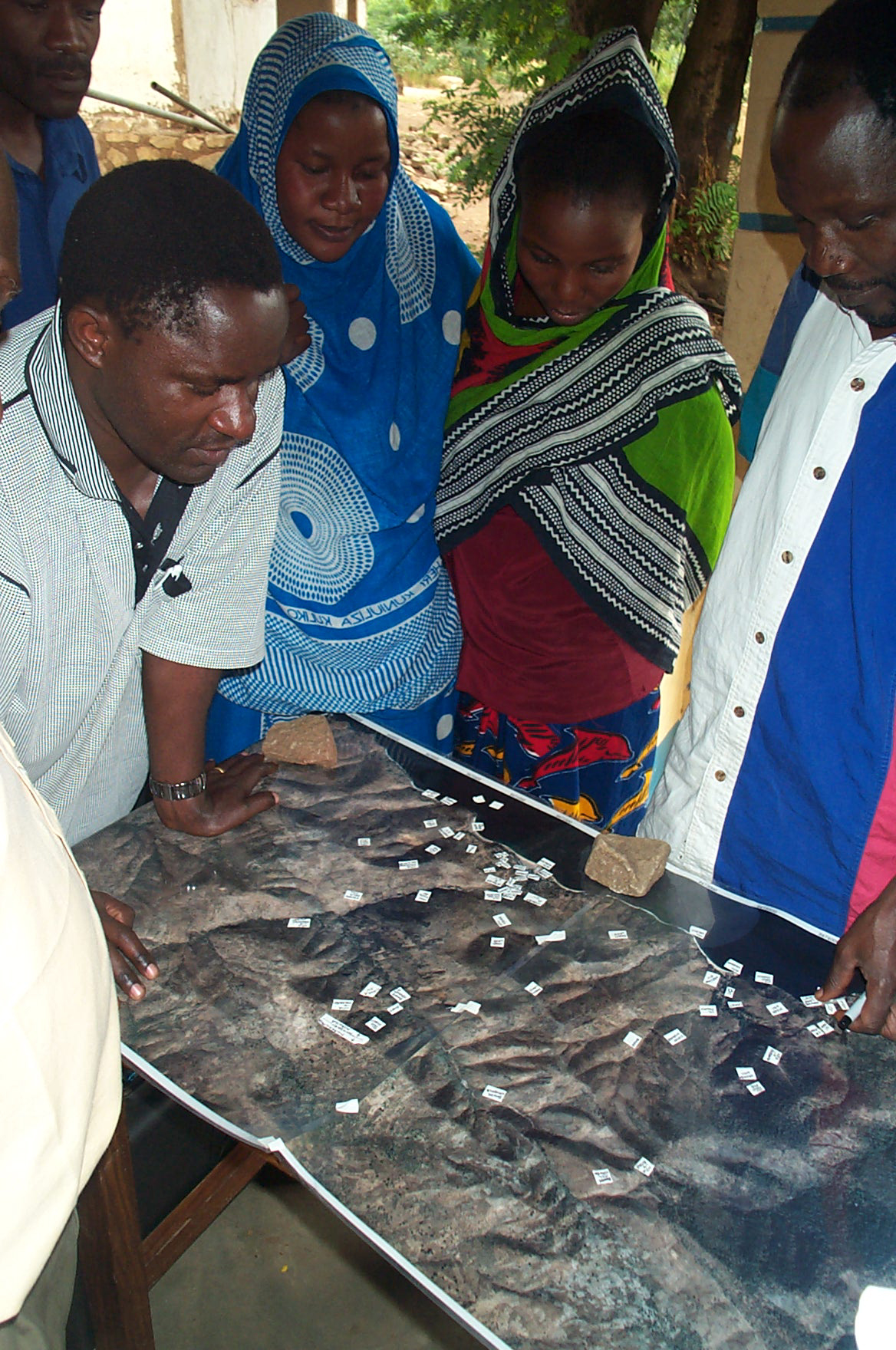 Villagers in Mtanga, Tanzania, gathered around a large printed satellite map of their community